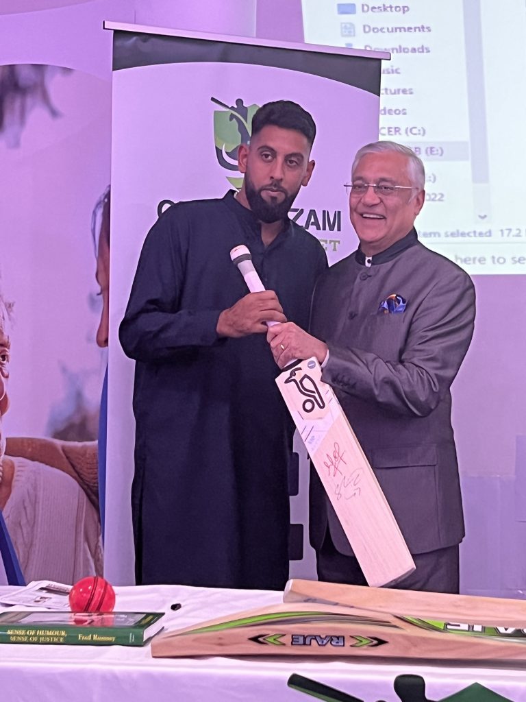 Kamlesh Patel presenting 1st raffle prize to Zishan Khalid Signed bat by Harris Rauf and Shadab Khan